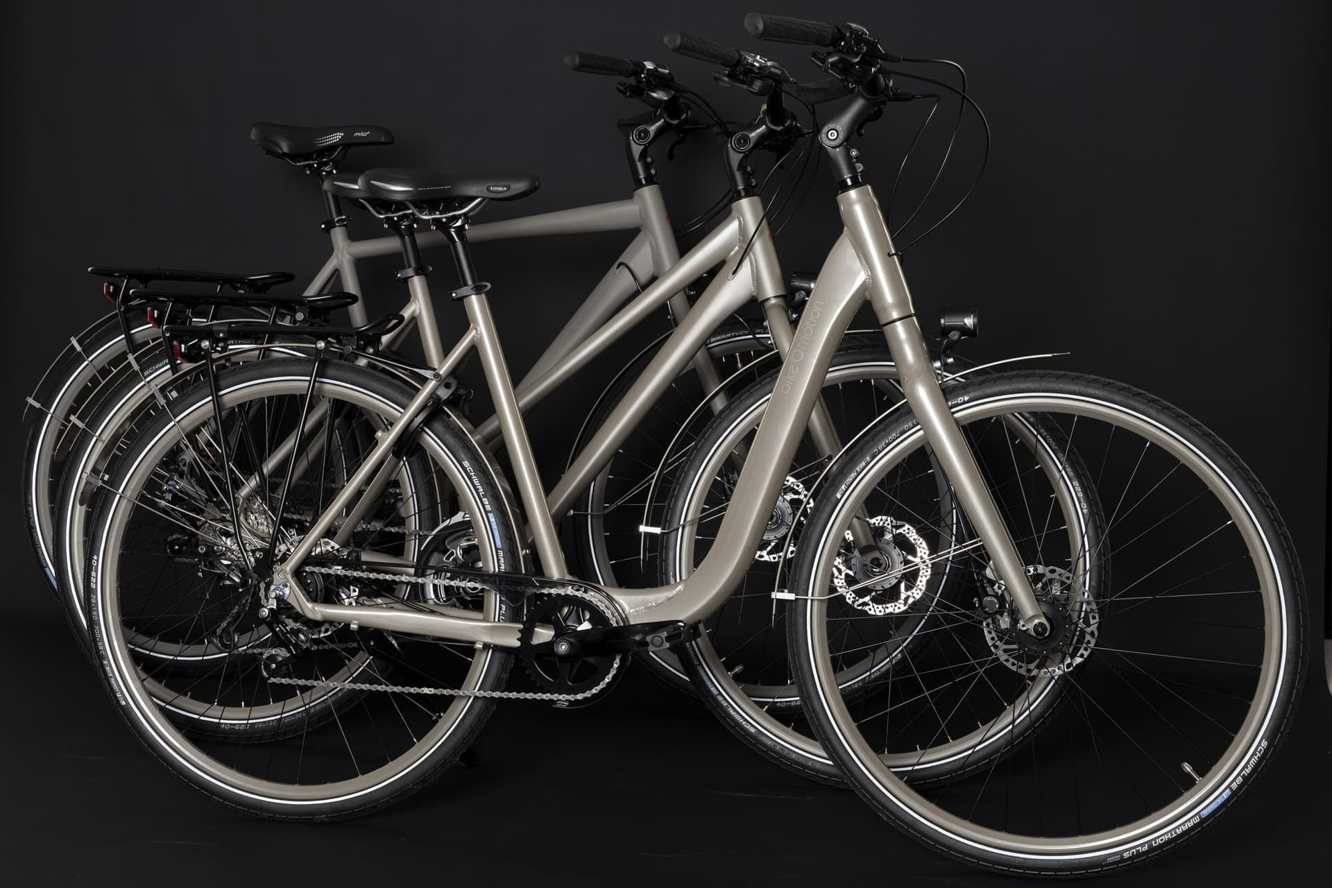 Drei bikeOmotion-Räder in Kupfer, Silber und Schwarz vor dunklem Hintergrund